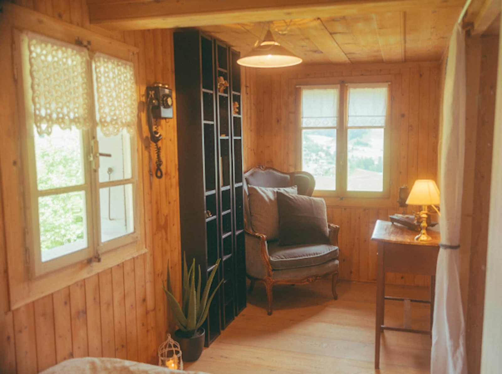 A velvet armchair and a vintage telephone in a pine-panelled corner, the valley framed in the window.