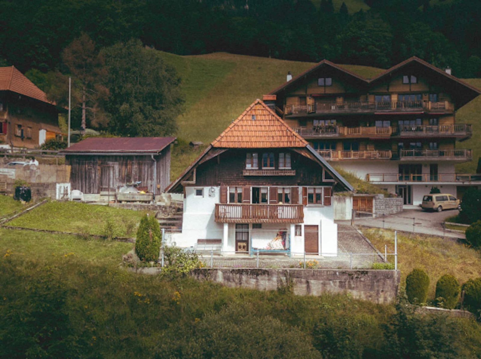 The century-old chalet on its own green plot, lawn and terrace wrapping the house, the pre-Alps beyond.